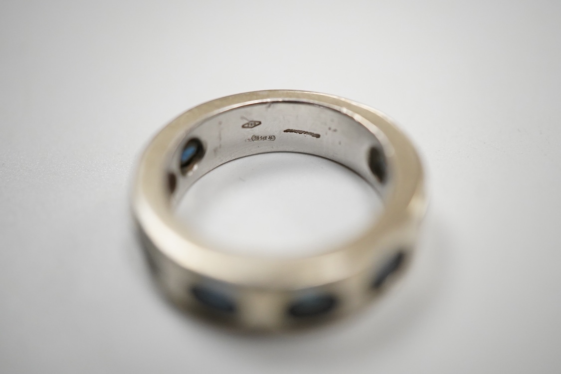 A recent Italian white metal (stamped 750) and seven stone gypsy set oval cut sapphire band, by Cristiano of Genoa, size N, gross weight 10.4 grams.